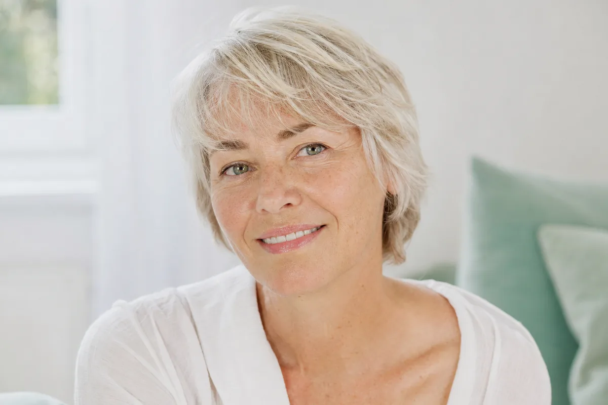 Woman in her fifties with an even, luminous complexion and natural freckles