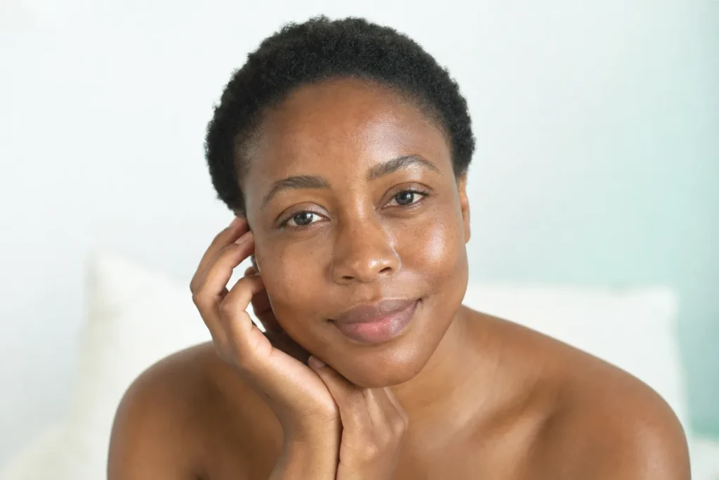 Woman with deep brown skin, a smooth relaxed forehead and soft expression lines
